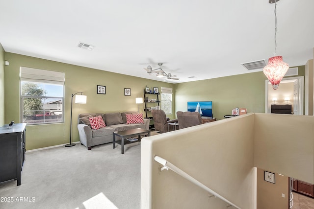 living area featuring baseboards, light colored carpet, visible vents, and ceiling fan