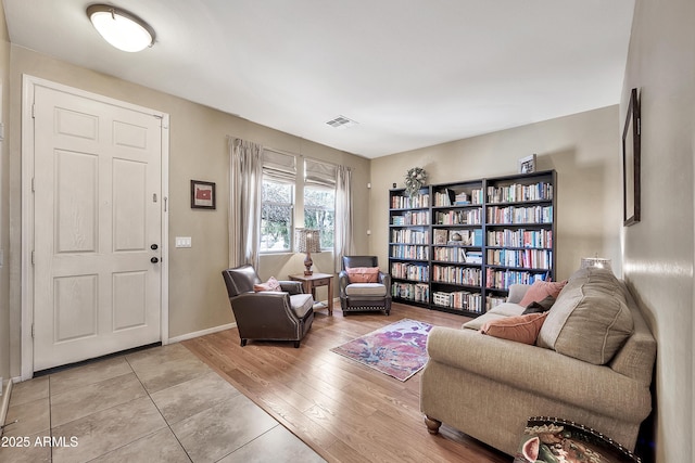 living area featuring visible vents, baseboards, and light wood finished floors