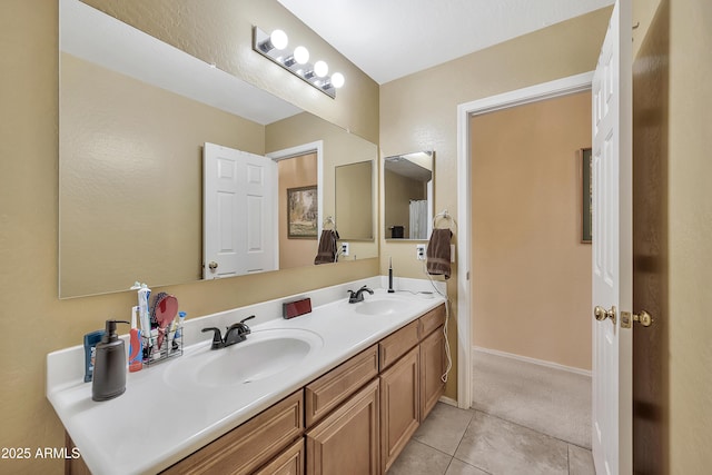 full bath featuring tile patterned floors, double vanity, baseboards, and a sink