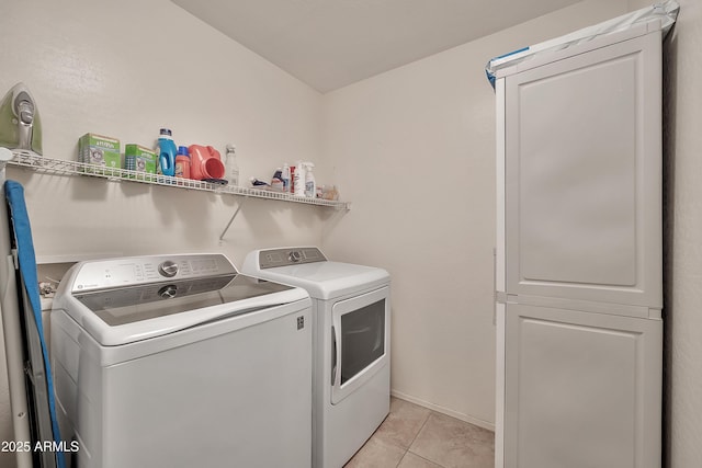 laundry area featuring washer and dryer, light tile patterned floors, and cabinet space