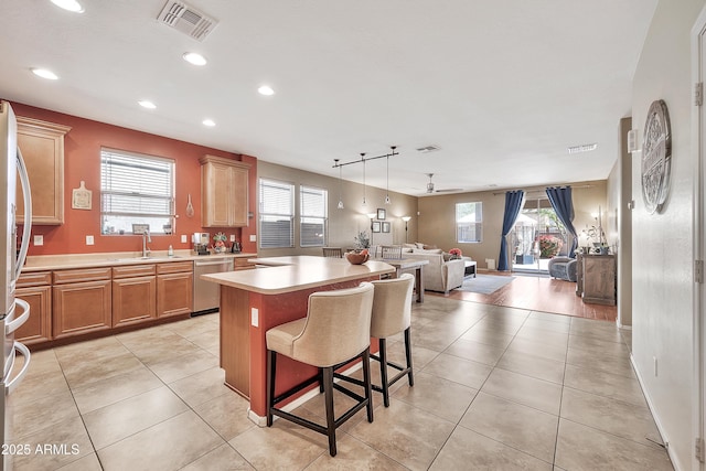 kitchen with light tile patterned floors, light countertops, appliances with stainless steel finishes, open floor plan, and a center island