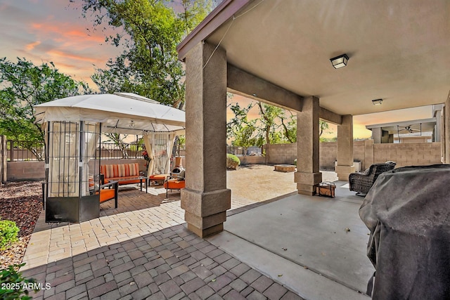 patio terrace at dusk featuring an outdoor living space with a fire pit, a fenced backyard, and a grill