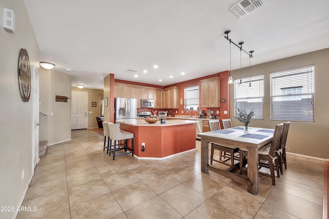 kitchen featuring visible vents, a kitchen island, appliances with stainless steel finishes, light tile patterned flooring, and light countertops