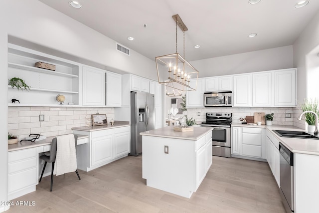 kitchen featuring appliances with stainless steel finishes, sink, decorative light fixtures, a center island, and white cabinetry