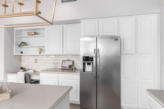 kitchen with decorative backsplash, stainless steel fridge, and white cabinetry