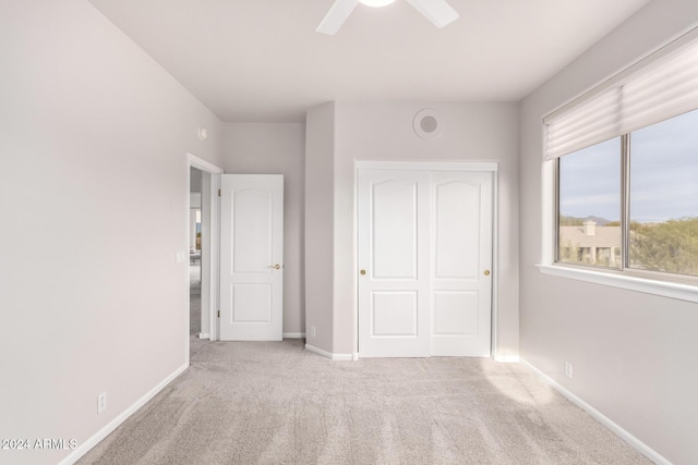 unfurnished bedroom with ceiling fan, light carpet, and a closet