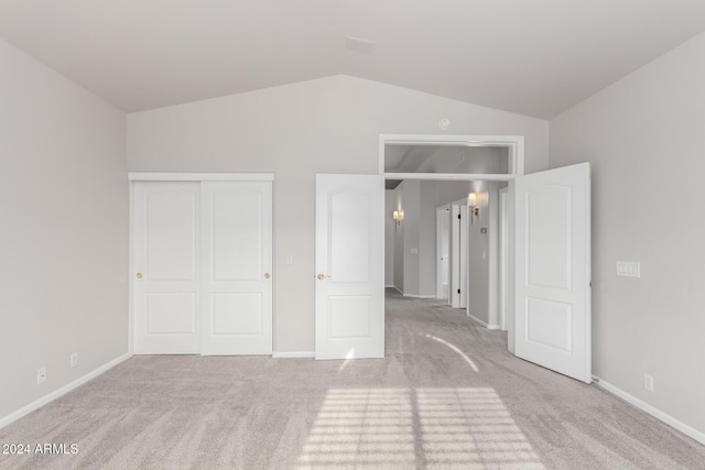 unfurnished bedroom featuring light carpet, vaulted ceiling, and a closet