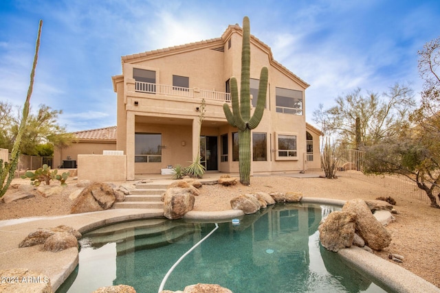 rear view of property featuring a balcony, a fenced in pool, and a patio