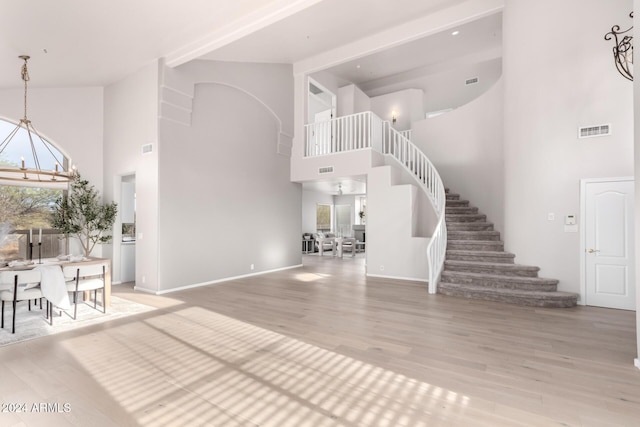 foyer entrance featuring a notable chandelier, wood-type flooring, a high ceiling, and a wealth of natural light