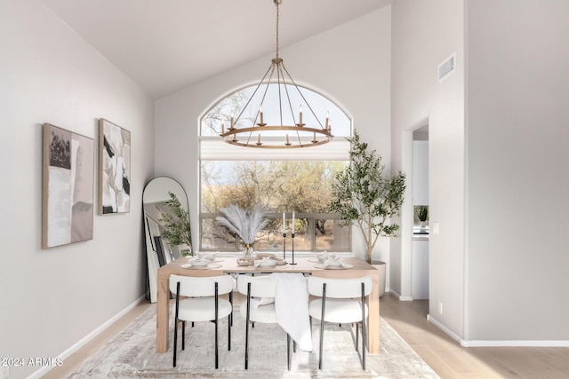 dining room with light hardwood / wood-style floors and high vaulted ceiling