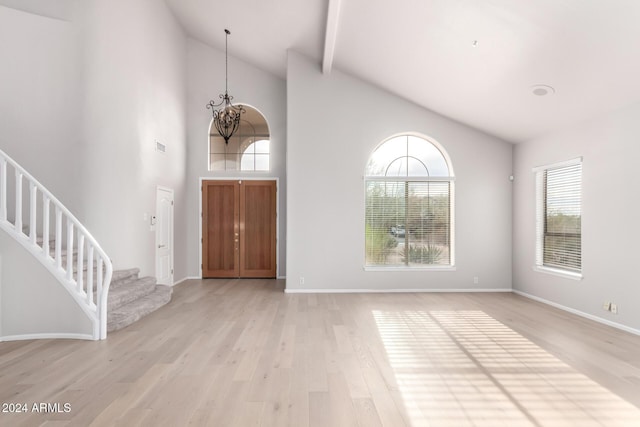 entrance foyer with light hardwood / wood-style floors, a towering ceiling, a wealth of natural light, and a chandelier