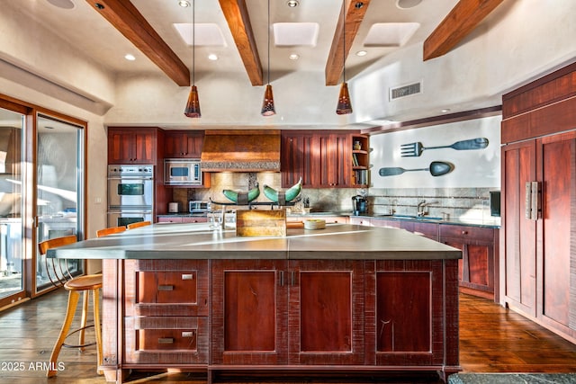 kitchen featuring a large island, beam ceiling, backsplash, and appliances with stainless steel finishes