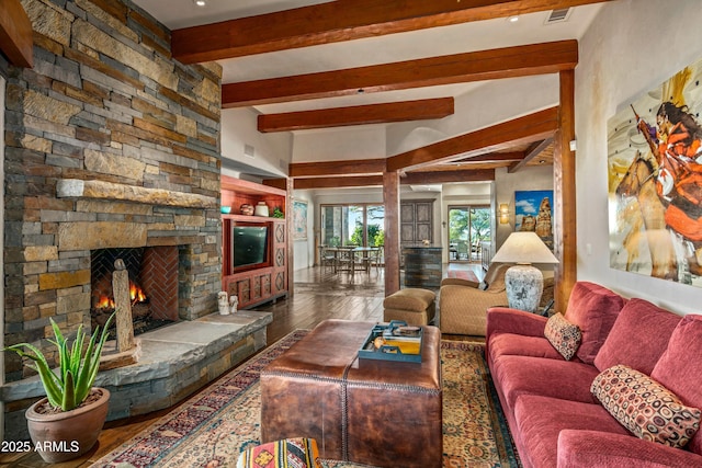 living room with beamed ceiling, built in shelves, hardwood / wood-style flooring, and a stone fireplace