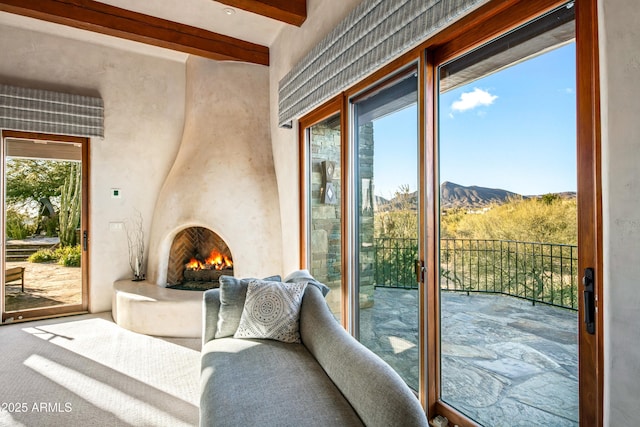 doorway to outside with beam ceiling, a mountain view, and a large fireplace