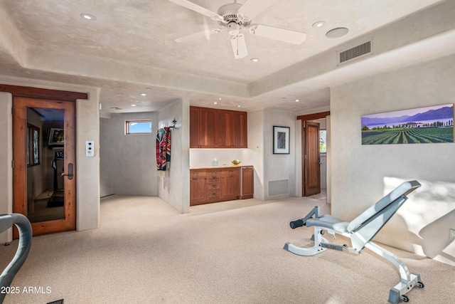 exercise area with ceiling fan and light colored carpet