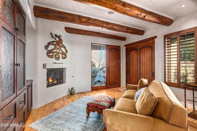 living room with beam ceiling and light wood-type flooring