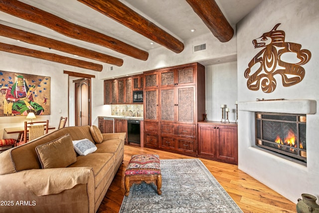 living room with beam ceiling, sink, and light wood-type flooring