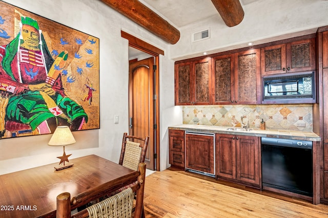 bar featuring decorative backsplash, sink, black appliances, light hardwood / wood-style flooring, and beamed ceiling