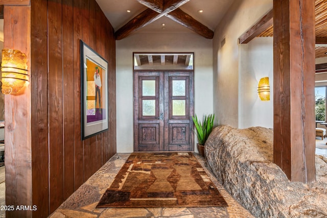 entryway with beam ceiling, plenty of natural light, and wood walls