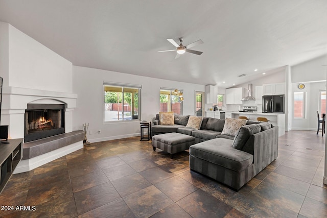 living room with a tiled fireplace, lofted ceiling, and ceiling fan