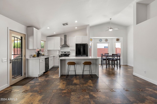 kitchen with wall chimney exhaust hood, sink, a kitchen island, stainless steel appliances, and white cabinets