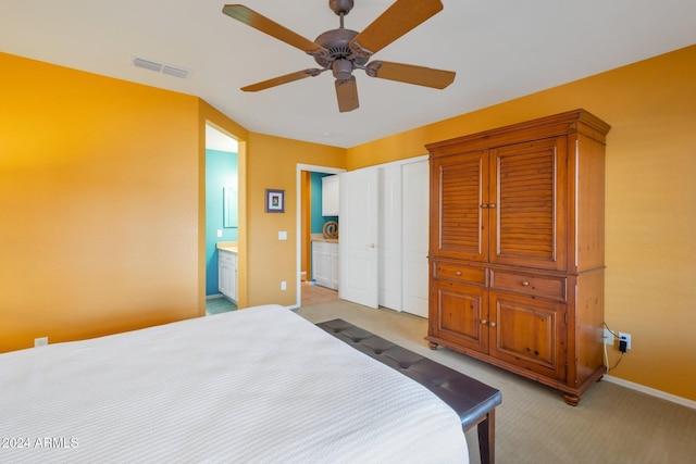 bedroom featuring light carpet, ensuite bath, and ceiling fan