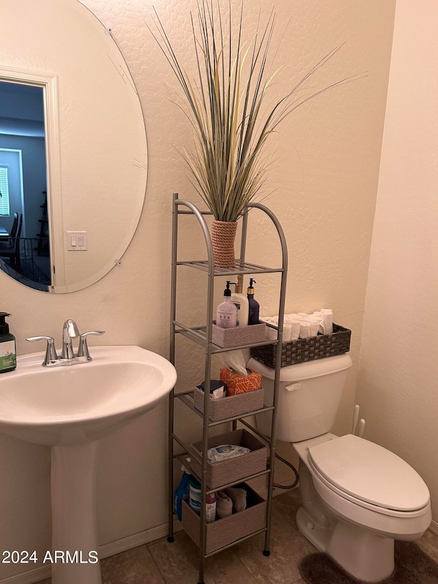 bathroom with toilet, tile patterned floors, and sink