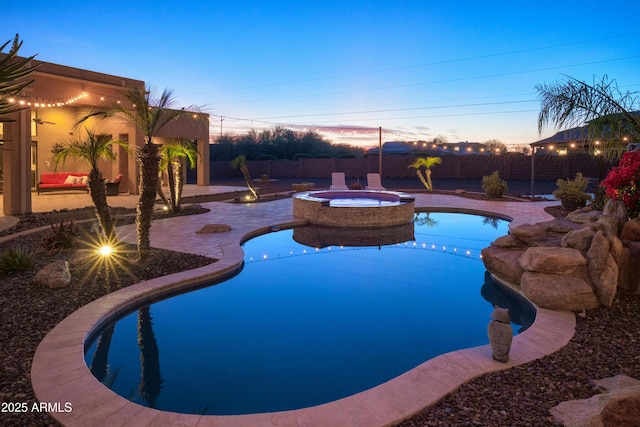 pool at dusk with an in ground hot tub