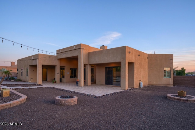 back house at dusk with a patio area and an outdoor fire pit