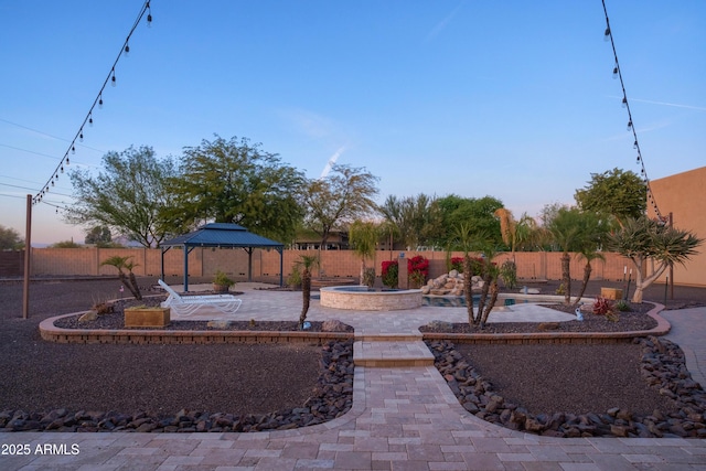 yard at dusk with a gazebo and a patio area