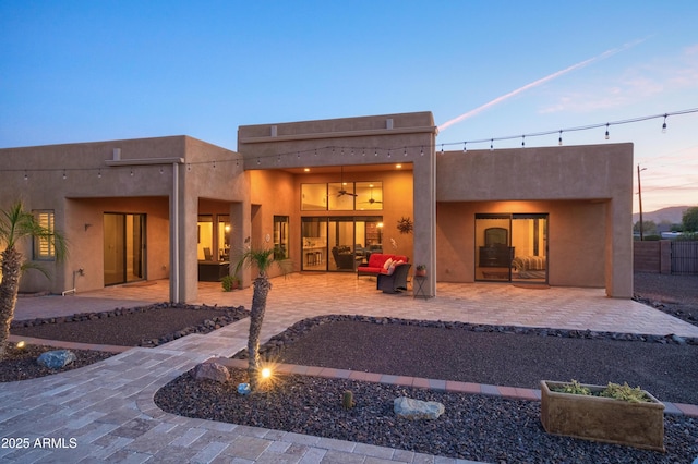 back house at dusk featuring a patio area and an outdoor hangout area