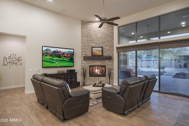 living room featuring a fireplace, a high ceiling, ceiling fan, and wood-type flooring