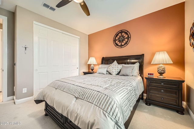 bedroom with baseboards, visible vents, a closet, and light colored carpet