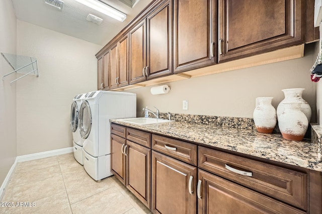 washroom featuring cabinet space, light tile patterned floors, visible vents, washer and clothes dryer, and a sink