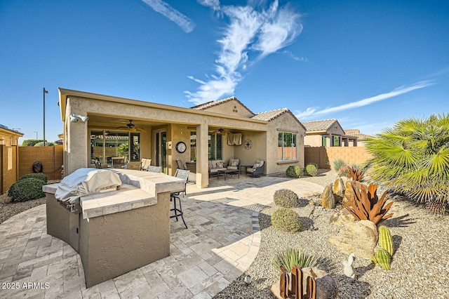 rear view of property featuring ceiling fan, an outdoor kitchen, a fenced backyard, an outdoor living space, and a patio area