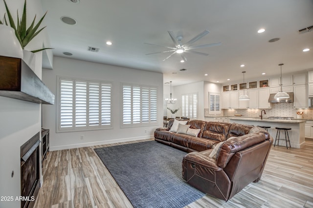 living area featuring light wood-style flooring, visible vents, and a fireplace