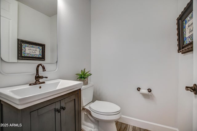 bathroom featuring vanity, toilet, wood finished floors, and baseboards