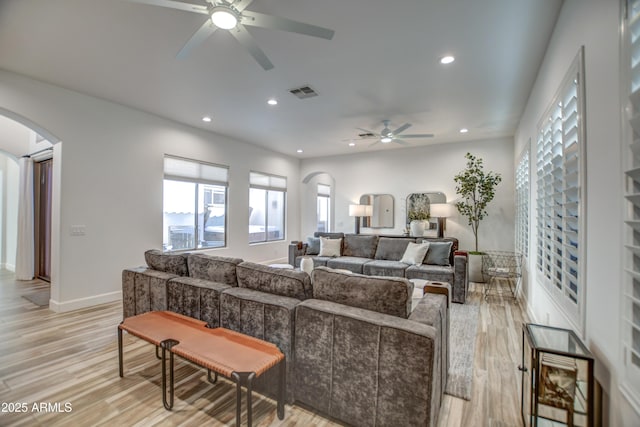 living area with light wood-type flooring, visible vents, recessed lighting, and arched walkways