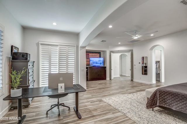 bedroom with baseboards, recessed lighting, arched walkways, and light wood-type flooring