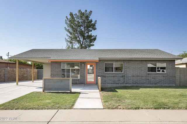 view of front of house with an attached carport, a front yard, fence, and a shingled roof