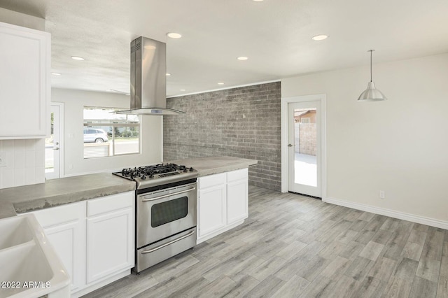 kitchen featuring stainless steel gas range oven, island exhaust hood, and white cabinetry