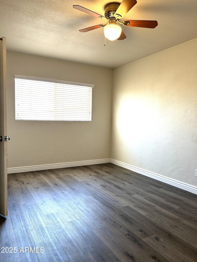 empty room with a ceiling fan, dark wood finished floors, a textured ceiling, and baseboards