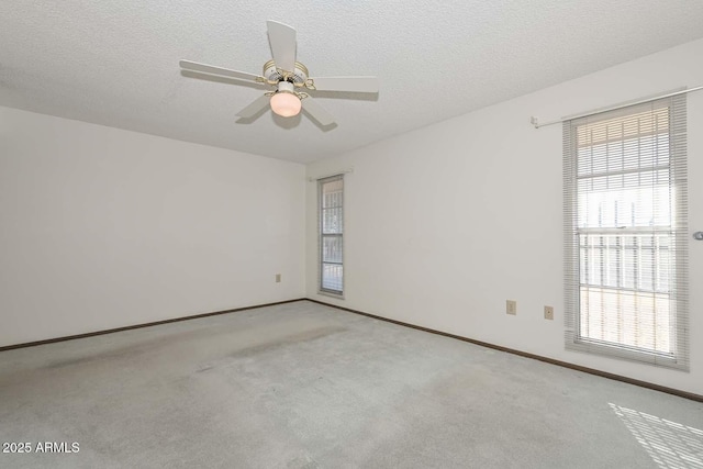 empty room with carpet flooring, ceiling fan, a textured ceiling, and baseboards