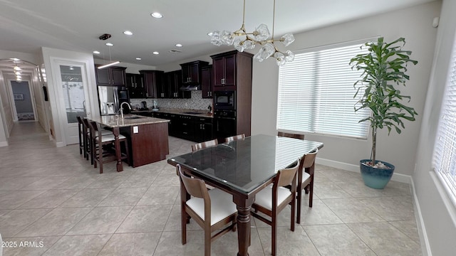 dining space featuring light tile patterned floors, a notable chandelier, and sink