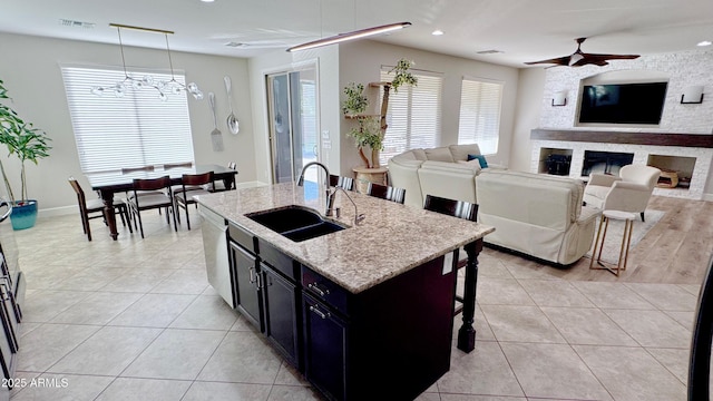 kitchen with a kitchen bar, sink, hanging light fixtures, dishwasher, and an island with sink