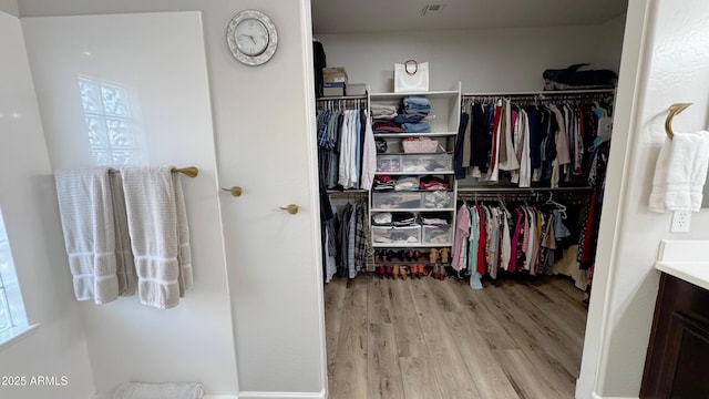 walk in closet with light hardwood / wood-style flooring