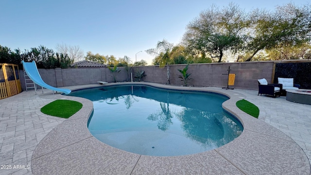 view of pool featuring a diving board, an outdoor fire pit, a patio, and a water slide