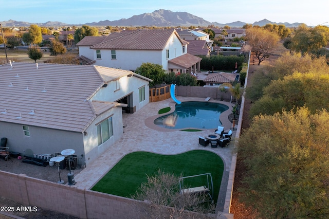 view of pool featuring a patio, a water slide, a yard, and a mountain view