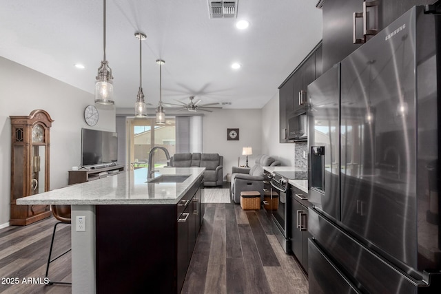 kitchen with visible vents, appliances with stainless steel finishes, open floor plan, a kitchen breakfast bar, and a sink