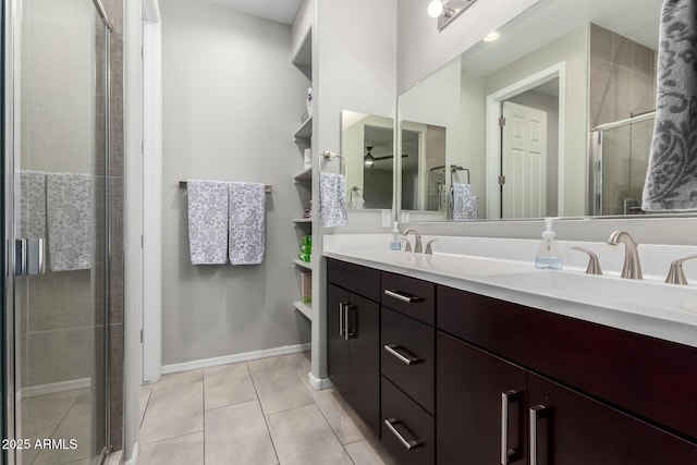 bathroom featuring double vanity, a sink, a shower stall, tile patterned flooring, and baseboards